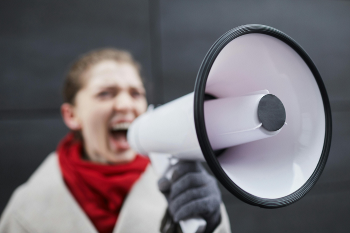 Una ragazza con il megafono in mano che urla la sua leadership