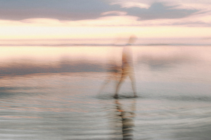 Uomo che cammina sulla spiaggia, immagine sfuocata sul tema dell’adattamento continuo