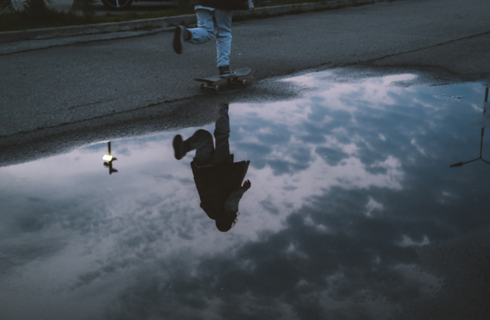 Skater riflesso in una pozzanghera, immagine di vulnerabilità ed equilibrio