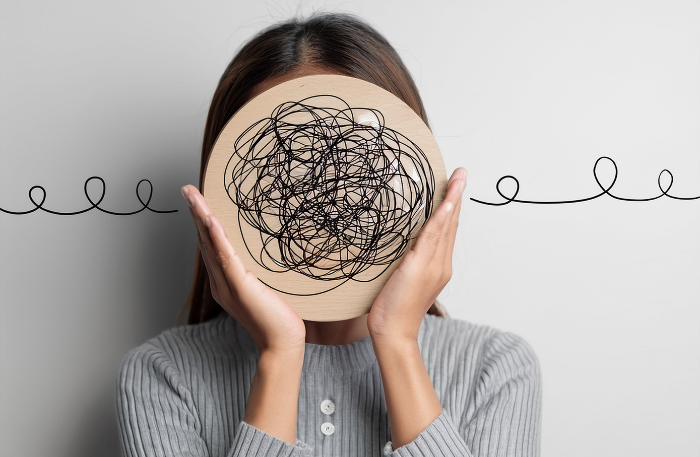 Ritratto di una giovane donna con un palloncino sopra la testa contenente un groviglio di fili intrecciati e confusi, metafora visiva dello skill mismatch e della confusione mentale quando le competenze non sono allineate al ruolo lavorativo.